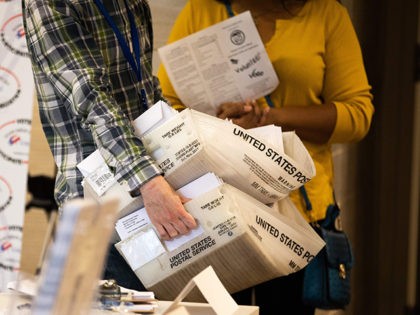 An absentee ballot election worker consolidates a large stack of absentee ballot applicati