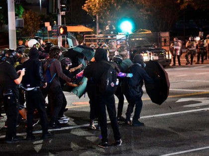 Protesters use umbrellas as shields from projectiles fired by Los Angeles County sheriff's