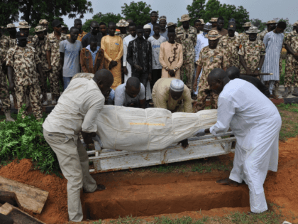 Nigerian soldiers and relatives look on as the body of a victim of the attack on vehicles