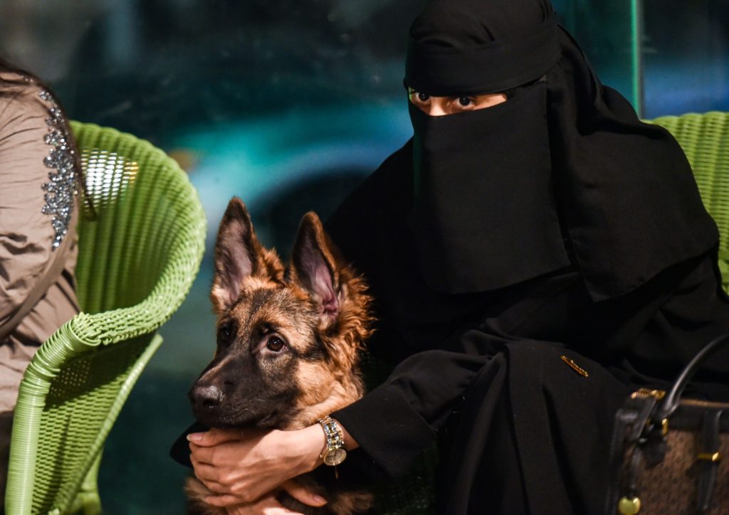 A woman sits with her German Shepherd at the "Barking Lot" cafe in Saudi Arabia's eastern Gulf city of Khobar, 450 kilometres east of the capital, on September 25, 2020. - Dog owners in Saudi Arabia can now enjoy a cup of coffee outside their home alongside their beloved pets in a new cafe -- a first for the ultra-conservative kingdom. The Barking Lot, which opened its doors in June in the coastal city of Khobar, has brought them much relief amid restrictions on animals in public places. Dogs are generally prohibited from walking in public and, unlike cats, are considered unclean in Islam, which originated in Saudi Arabia. (Photo by FAYEZ NURELDINE / AFP) (Photo by FAYEZ NURELDINE/AFP via Getty Images)