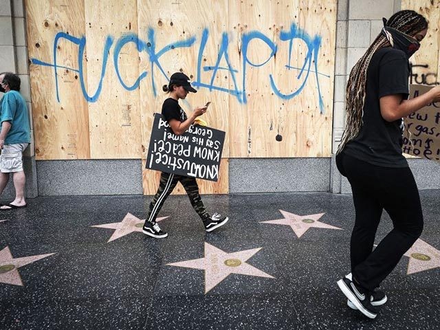 LOS ANGELES, CALIFORNIA - JUNE 02: Protesters walk along the Hollywood Walk of Fame, with 'Fuck LAPD' scrawled on a boarded up window, during a peaceful demonstration over George Floyd’s death on June 2, 2020 in Los Angeles, California. California Governor Gavin Newsom has deployed National Guard troops to Los …