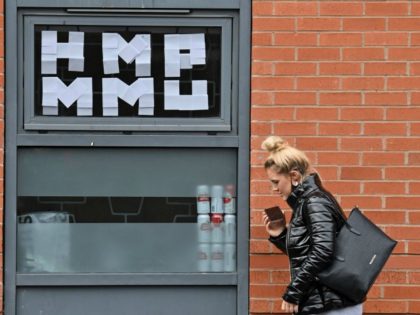 A woman walks past messages pasted inside the windows of the Cambridge Halls student accommodation, for students at Manchester Metropolitan University, in Manchester, north-west England on September 28, 2020, as many students live in a temporary lock-down in a bid to reduce the spread of the novel coronavirus covid-19 on …