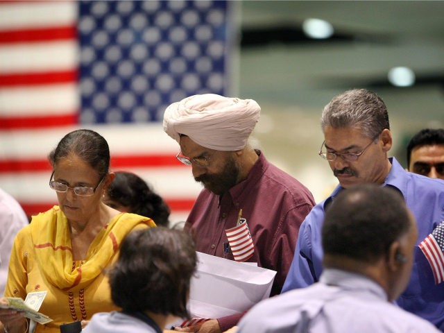 Amrik Sidhu (C) and his wife Harjinder Sidhu (L), both Sikhs from India, apply for their p