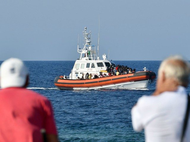 Men watch as migrants from Tunisia and Lybia arrive onboard of an Italian Guardia Costiera (Coast Guard) boat in the Italian Pelagie Island of Lampedusa on August 1, 2020. (Photo by Alberto PIZZOLI / AFP) (Photo by ALBERTO PIZZOLI/AFP via Getty Images)