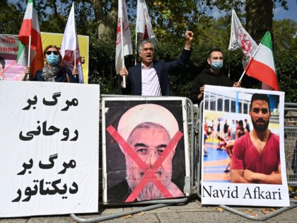 Protesters wave the Lion and Sun flag of the National Council of Resistance of Iran and the white flag of the People's Mujahedin of Iran, two Iranian opposition groups, with a placard depicting the crossed out face of Iran's President Hassan Rouhani as they demonstrate outside the Iranian embassy in …