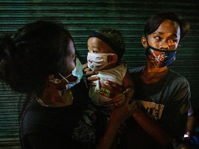 MANILA, PHILIPPINES - AUGUST 7: A homeless teenage couple carry their months-old infant as they queue to receive free meals from volunteers on August 7, 2020 in Caloocan, Metro Manila, Philippines. The Philippine economy suffered its worst slump on record in the second quarter, falling into recession for the first …