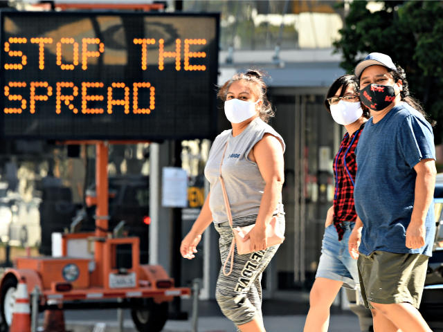 FILE - Pedestrians wear masks as they walk in front of a sign reminding the public to take steps to stop the spread of coronavirus, Thursday, July 23, 2020, in Glendale, Calif. Los Angeles County is seeing some hopeful signs amid the coronavirus surge. The county reported Wednesday that COVID-19 …