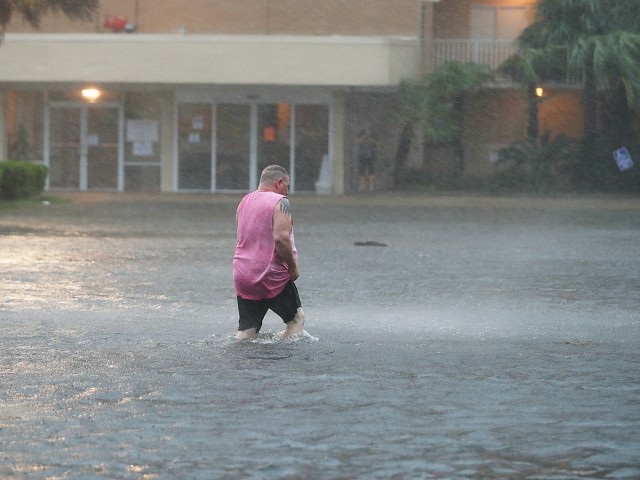 GULF SHORES, ALABAMA - SEPTEMBER 15: A man walks though a flooded parking lot as the outer bands of Hurricane Sally come ashore on September 15, 2020 in Gulf Shores, Alabama. The storm is bringing heavy rain, high winds and a dangerous storm surge from Louisiana to Florida. (Photo by Joe Raedle/Getty Images)