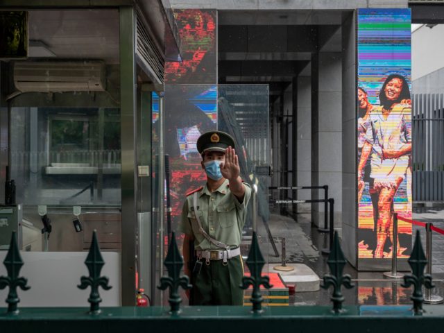 A Chinese paramilitary police officer gestures while standing at the entrance gate of the