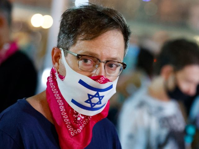 An Israeli man wearing a face mask with the national flag, takes part in a demonstration against the Prime Minister and an imminent and unprecedented second nationwide lockdown to tackle a spike in coronavirus, in the coastal city of Tel Aviv, on September 17, 2020. - The measures will be …