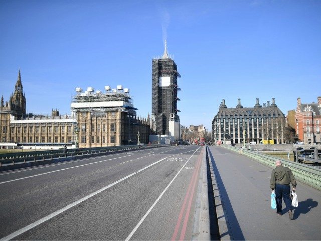 TOPSHOT - A picture shows the Houses of Parliament (L) at the end of an empty Westminster Bridge with one pedestrian on the pavement in central London in the morning on March 24, 2020 after Britain ordered a lockdown to slow the spread of the novel coronavirus. - Britain was …
