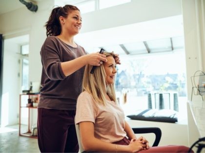 Smiling young woman discussing her hairstyle with a salon stylist - stock photo
