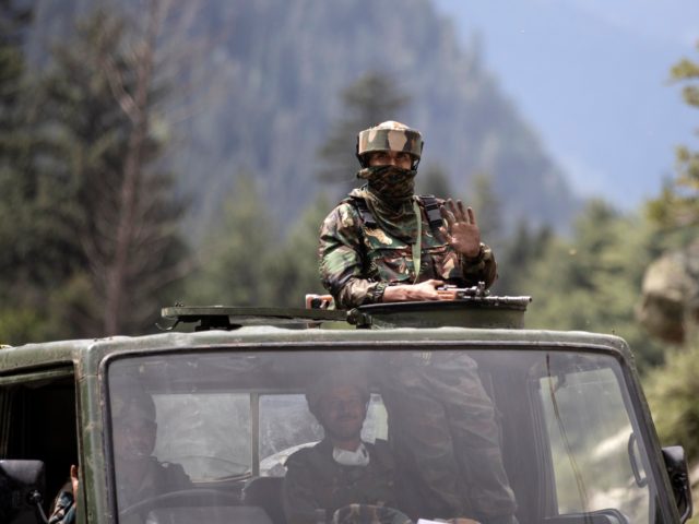 An Indian army soldier keeps guard on top of his vehicle as their convoy moves on the Srin