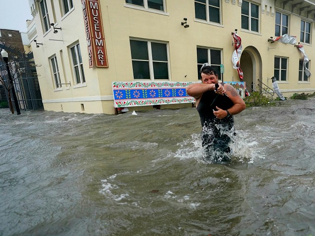 Trent Airhart wades through floodwaters, Wednesday, Sept. 16, 2020, in downtown Pensacola, Fla. Hurricane Sally made landfall Wednesday near Gulf Shores, Alabama, as a Category 2 storm, pushing a surge of ocean water onto the coast and dumping torrential rain that forecasters said would cause dangerous flooding from the Florida Panhandle to Mississippi and well inland in the days ahead.(AP Photo/Gerald Herbert)