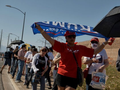 Keti Fusitua, from Las Vegas, holds a flag over herself, shielding the sun, as she waits i