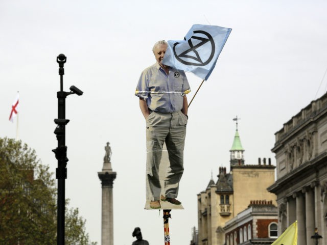 A cardboard cutout of David Attenborough is held up as protesters march toward parliament with Nelson's Column in the background, in London, Tuesday April 23, 2019, during a climate protest. The non-violent protest group, Extinction Rebellion, is seeking negotiations with the government on its demand to make slowing climate change …