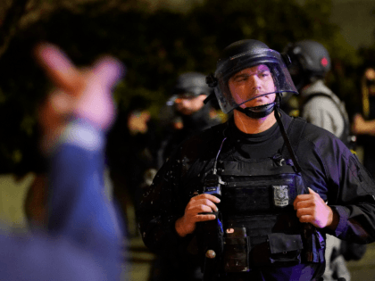 A protestor reacts towards a Portland police officer during protests, Saturday, Sept. 26, 2020, in Portland. The protests which began since the police killing of George Floyd in late May often result frequent clashes between protesters and law enforcement. (AP Photo/John Locher)