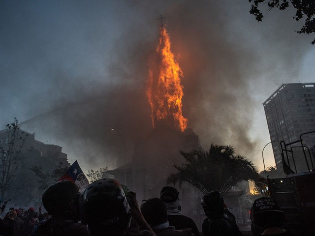 SANTIAGO, CHILE - OCTOBER 18: Firemen attempt to put out a church which has caught fire during a protest on October 18, 2020 in Santiago, Chile. A series of protests and social unrest arose on October 18, 2019, after a subway fare increase. It developed in a movement demanding improvements …