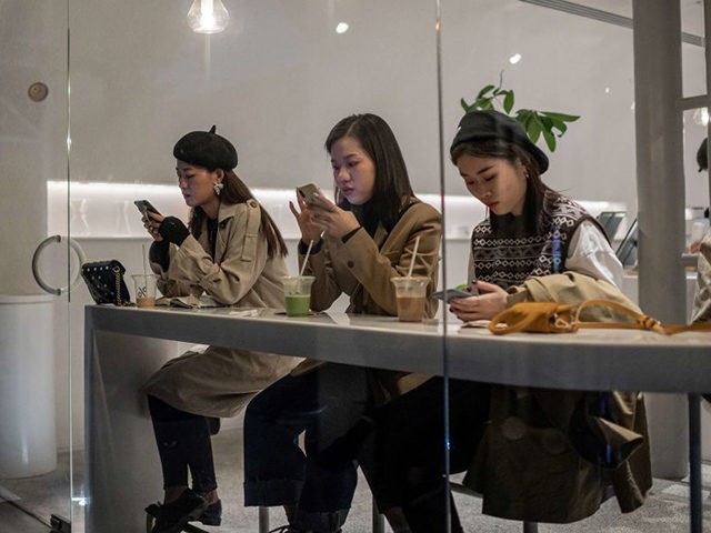 This picture taken on October 18, 2020 shows people looking at their phones as they sit inside a coffee shop in the 798 art district in Beijing. (Photo by NICOLAS ASFOURI / AFP) (Photo by NICOLAS ASFOURI/AFP via Getty Images)