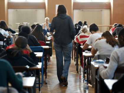 A teacher walks through a classroom as high school students take the philosophy exam, the