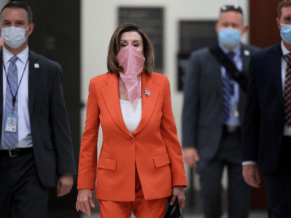 Wearing a scarf over her mouth and nose, Speaker of the House Nancy Pelosi (D-CA) is surrounded by security and staff as she arrives for her weekly news conference during the novel coronavirus pandemic at the U.S. Capitol April 24, 2020 in Washington, DC. President Donald Trump is expected to …