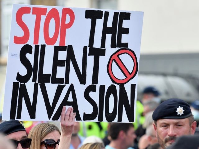 TOPSHOT - An anti-immigation protester holds up a placard during a demo in Dover on the south-east coast of England, on September 5, 2020, as pro-and anti-migrant demonstrations take place in the town. - Nearly 1,500 migrants and asylum seekers arrived in Britain by small boats in August, according to …