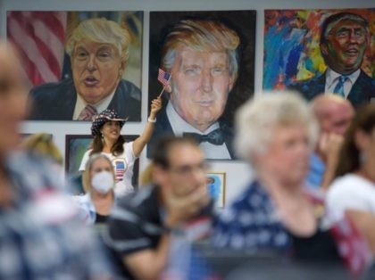 TOPSHOT - A woman waves an American flag as President Trump supporters watch the president