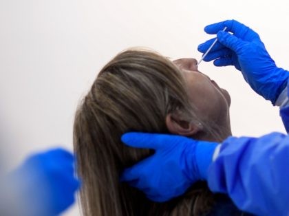 A medical worker of the Medical Emergency Services of Madrid (SUMMA 112) takes a swab sample from a woman at the Lope de Vega Cultural Center in the Vallecas neighbourhood, in Madrid, on October 1, 2020 while testing for potential coronavirus disease cases. - Spain's government published a decree extending …