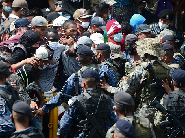 Honduran migrants break the police fence to enter Guatemala on their way to the US, in the