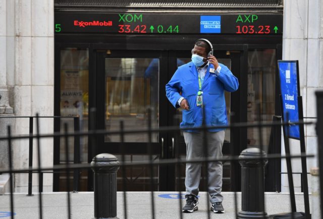 A stock trader checks his headphones outside the New York Stock Exchange (NYSE) in lower M