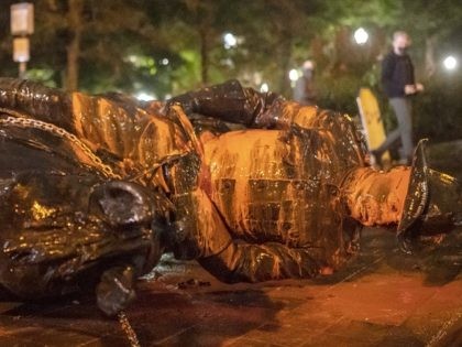 PORTLAND, OR - OCTOBER 11: Protesters walk past a toppled statue of President Theodore Roosevelt during an Indigenous Peoples Day of Rage protest on October 11, 2020 in Portland, Oregon. Protesters tore down statues of two U.S. presidents and broke windows out of downtown businesses Sunday night before police intervened. …