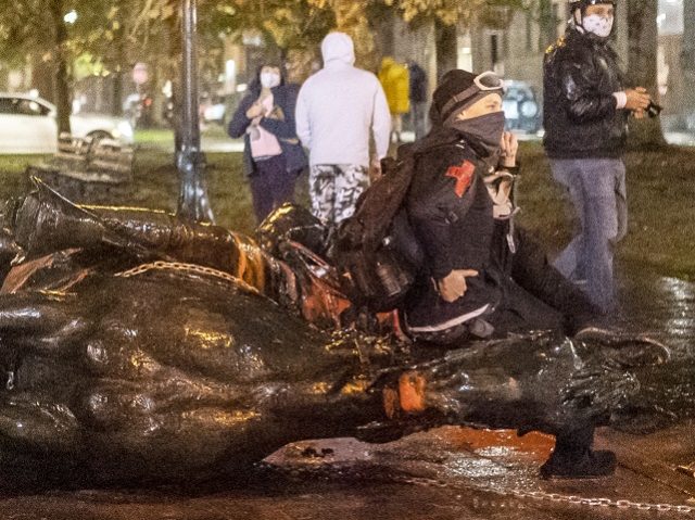 PORTLAND, OR - OCTOBER 11: Protesters stand over a toppled statue of President Theadore Rosevelt during an Indigenous Peoples Day of Rage protest on October 11, 2020 in Portland, Oregon. Protesters tore down statues of two U.S. presidents and broke windows out of downtown businesses Sunday night before police intervened. …