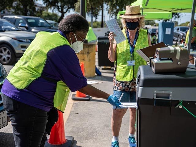 AUSTIN, TX - OCTOBER 13: Workers drop voters ballots into a secure box at a ballot drop off location on October 13, 2020 in Austin, Texas. The first day of voting saw voters waiting hours in line to cast their votes. Gov. Greg Abbott announced earlier this year that he …