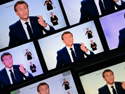 This picture shows screens displaying French President Emmanuel Macron as he addresses the
