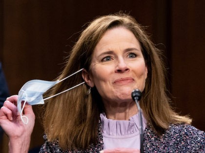 WASHINGTON, DC - OCTOBER 14: Supreme Court nominee Judge Amy Coney Barrett takes off her mask after returning from a break while testifying before the Senate Judiciary Committee on the third day of her Supreme Court confirmation hearing on Capitol Hill on October 14, 2020 in Washington, DC. Barrett was …