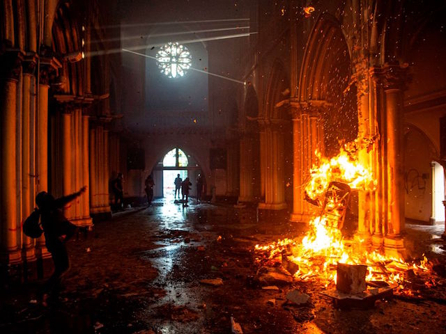 TOPSHOT - View of a fire set up by demonstrators inside the San Francisco de Borja church during clashes with riot police on the commemoration of the first anniversary of the social uprising in Chile, in Santiago, on October 18, 2020, as the country prepares for a landmark referendum. - Two churches were torched as tens of thousands of demonstrators gathered Sunday in a central Santiago square to mark the anniversary of a protest movement that broke out last year demanding greater equality in Chile. The demonstration comes just a week before Chileans vote in a referendum on whether to replace the dictatorship-era constitution -- one of the key demands when the protest movement began on October 18, 2019. (Photo by MARTIN BERNETTI / AFP) (Photo by MARTIN BERNETTI/AFP via Getty Images)