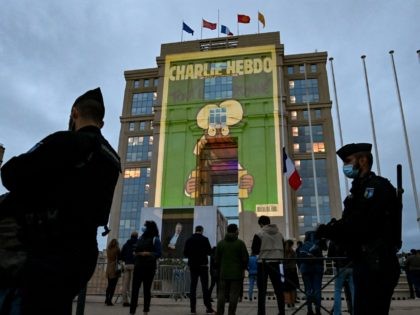 People look at cartoons of French satirical weekly newspaper Charlie Hebdo projected onto the facade of the Hotel de Region in Montpellier, on October 21, 2020, during a national homage to French teacher Samuel Paty who was beheaded for showing cartoons of the Prophet Mohamed in his civics class. - …