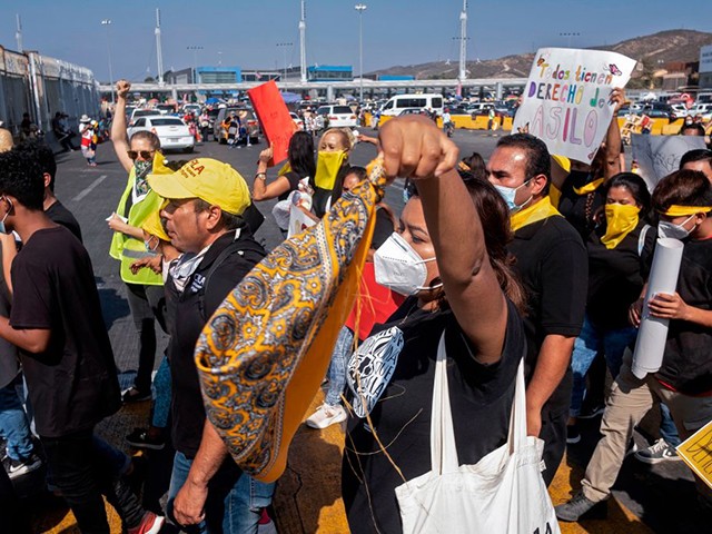 Migrants and human rights activists protest against US and Mexican migration policies at the San Ysidro crossing port, in Tijuana, Baja California state, Mexico, on the border with the US, on October 21, 2020, amid the new coropnavirus pandemic. - With the implementation of the Migrant Protection Protocol (MPP), asylum seekers were forced to remain in Mexico while their migration cases were processed. But, due to the COVID-19 pandemic, US authorities suspended most asylum procedures leaving thousands of migrants stranded along the border. (Photo by Guillermo Arias / AFP) (Photo by GUILLERMO ARIAS/AFP via Getty Images)