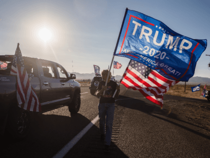 A woman waves a Trump and a US National flag as a caravan of cars from Kingman drives past supporting President Trump, as they gather for a presidential debate watch party, in Golden Valley, Arizona on October 22, 2020. (Photo by ARIANA DREHSLER / AFP) (Photo by ARIANA DREHSLER/AFP via …