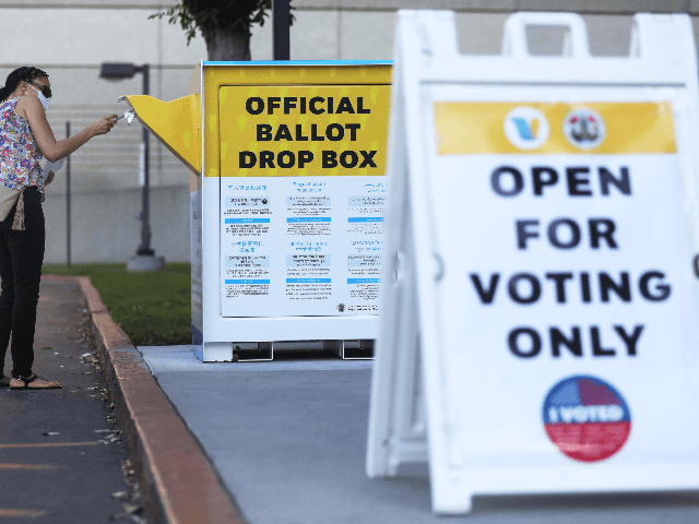 A pedestrian places a ballot in an official mail-in ballot drop box outside of the L.A. Co