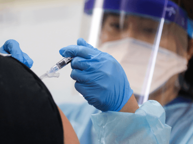 A nurse gives a flu vaccination shot to a man at a free clinic held at a local library on