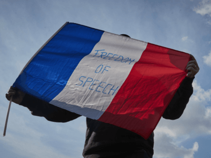 PARIS, FRANCE - OCTOBER 18: A protestor waves a French Tricolor flag with 'Freedom of Speech' written on it during an anti-terrorism vigil at Place de La Republique for the murdered school teacher Samuel Paty who was killed in a terrorist attack in the suburbs of Paris on October 18, …