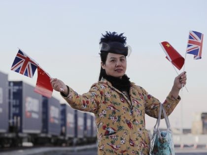 BARKING, ENGLAND - JANUARY 18: A woman holds a Union flag and a Chinese Flag as a train engine pulls carriages that started their Journey in Yiwu in China into Barking rail freight terminal on January 18, 2017 in Barking, England. After travelling for 16 days and covering around 7,456 …