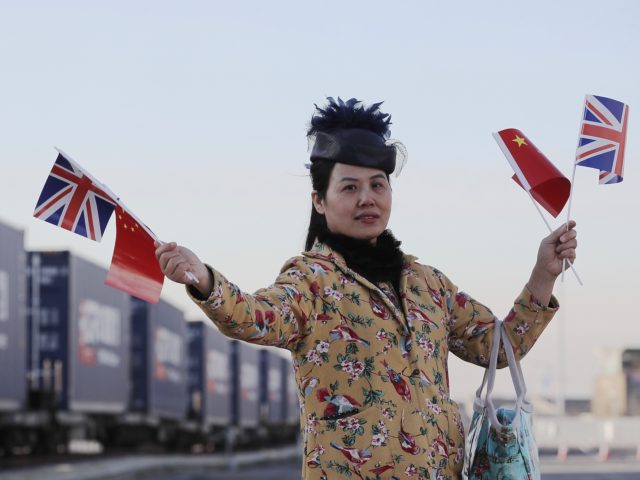 BARKING, ENGLAND - JANUARY 18: A woman holds a Union flag and a Chinese Flag as a train en