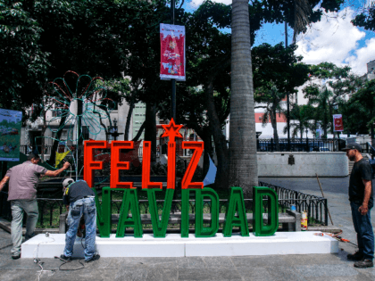 Men work on the installation of a christmas sign in Caracas on November 2, 2017. Venezuela will put into circulation a new bank note of 100,000 Bolivars, which multiplies by five the current largest denomination, and will move towards the massive use of electronic money to avoid what President Nicolas …