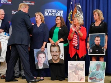US President Donald Trump greets people holding posters of people allegedly killed by illegal immigrants before speakong on immigration in the South Court Auditorium, next to the White House on June 22, 2018 in Washington, DC. (Photo by Mandel NGAN / AFP) (Photo credit should read MANDEL NGAN/AFP via Getty …
