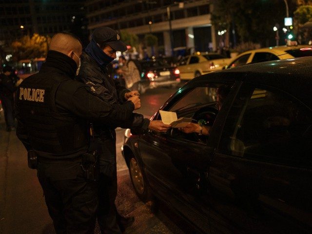 A police officer checks the documents of a driver verifying permission of movement in Athens on October 25, 2020. - Greek Prime Minister Kyriakos Mitsotakis on October 23 declared a night curfew in Athens, Thessaloniki and other areas to curb the spread of the novel coronavirus. (Photo by Angelos Tzortzinis …