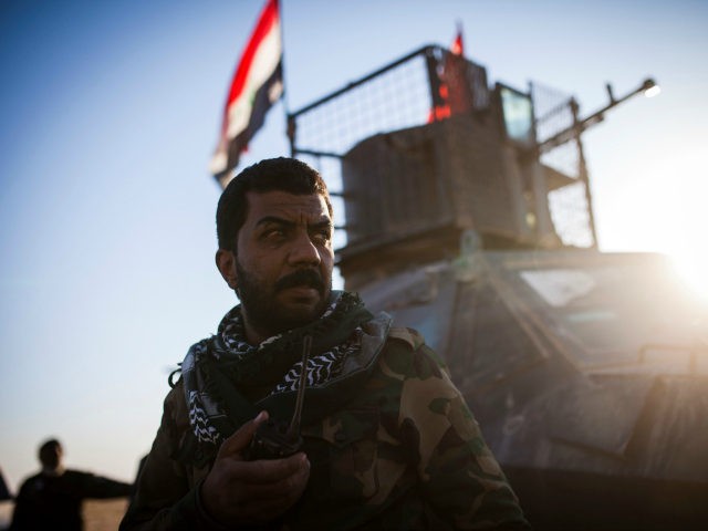 A member of the Hashd Al Shaabi (Popular Mobilisation Units), looks towards the direction of incoming snipper fire at Tal Afar airport on November 20, 2016. Pro-government paramilitary forces advancing on the town of Tal Afar, which commands the city's western approaches, entered its airport, while troops moving up from …