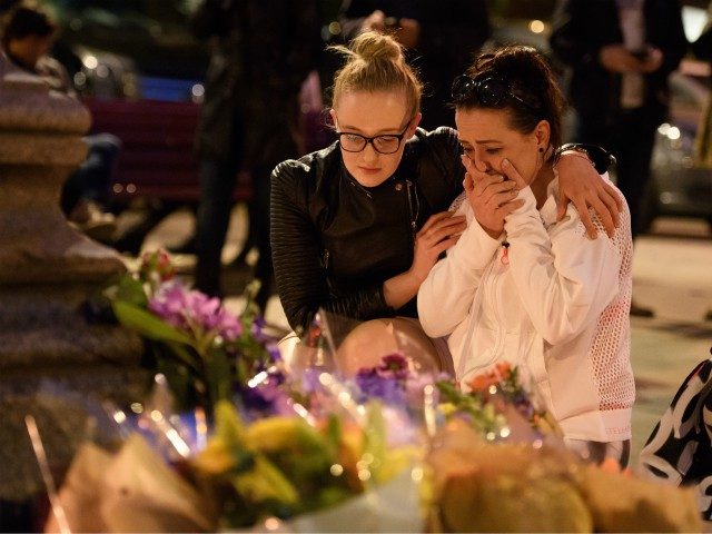 MANCHESTER, ENGLAND - MAY 23: A woman is consoled as she looks at the floral tributes foll