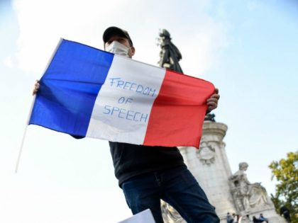 A woman holds a placard reading "History course for eveyone" and a man holds a French flag as they gather on Place de la Republique in Paris on October 18, 2020, in homage to history teacher Samuel Paty two days after he was beheaded by an attacker who was shot …